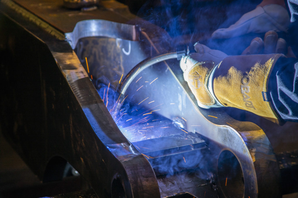 Closeup of welder welding on a large heavy equipment component 