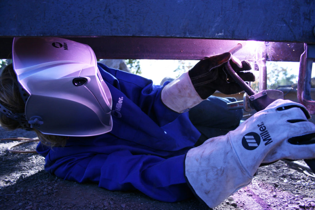 Welding operator on his back welding out of position with a self-shielded FCAW gun