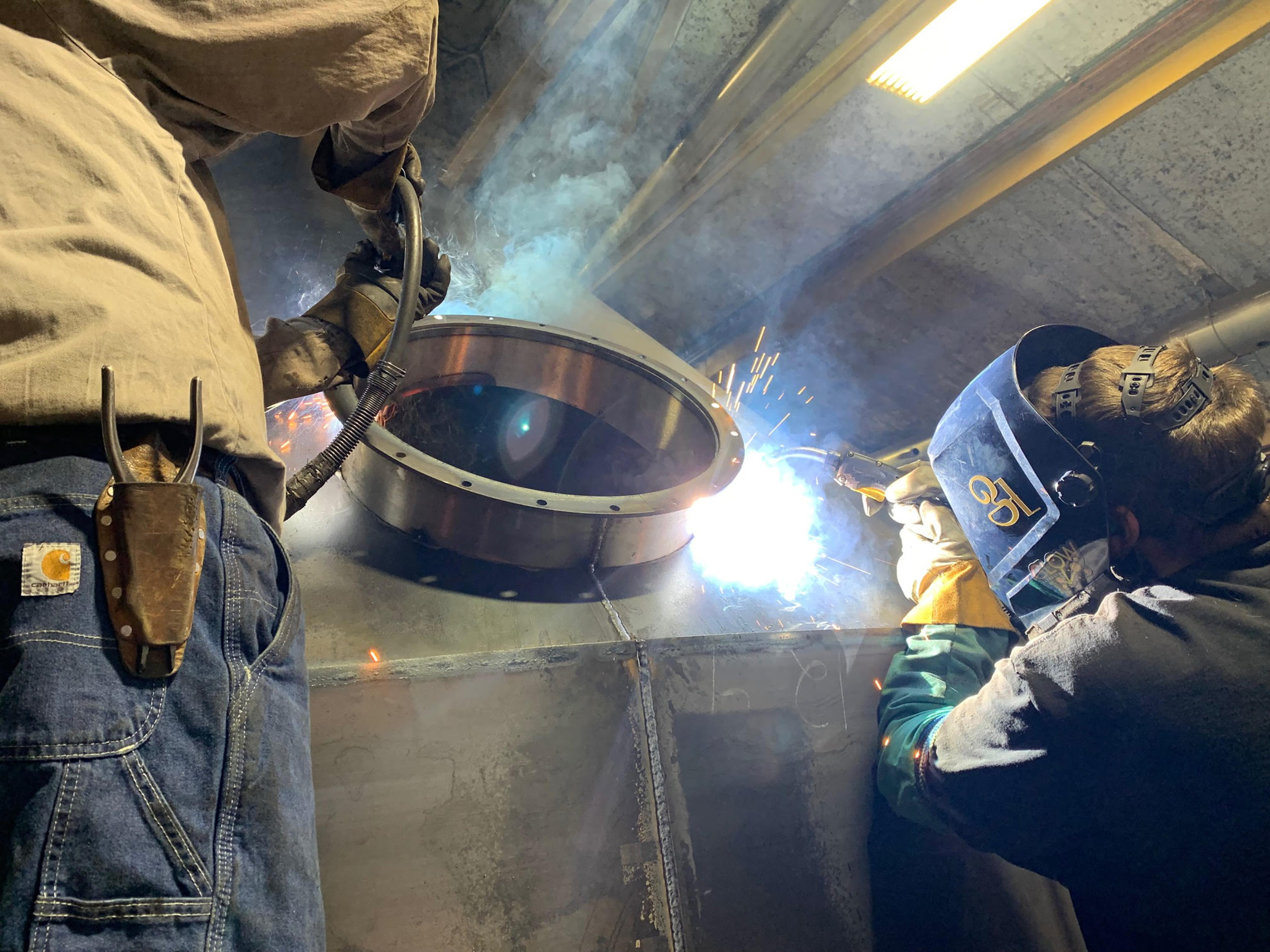Closeup of two welding operators welding on a tank for concrete